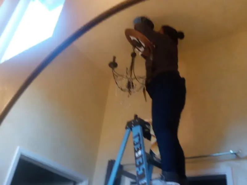 Electrician installing a chandelier in a Rose Hill residence